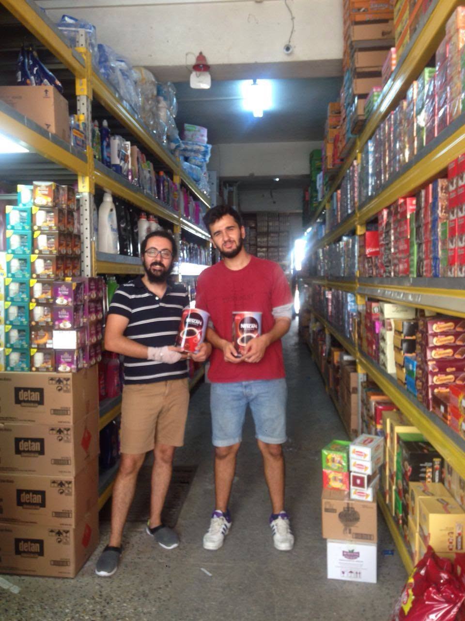 Two organizers picking up supplies, including coffee, at a local grocer